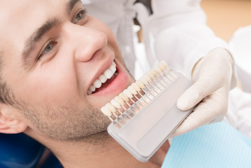 Man smiling while sitting in dental chair receiving cosmetic dentistry services